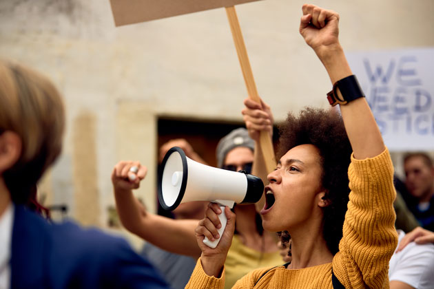 Black woman shouting into a bullhorn at a protest