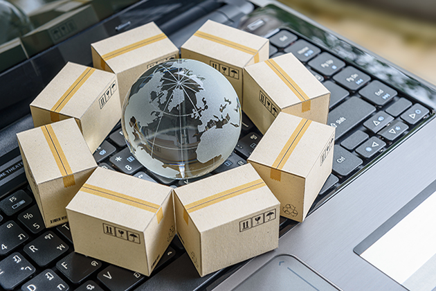 A laptop keyboard with a glass globe on it, surrounded by a circle of shipping boxes.
