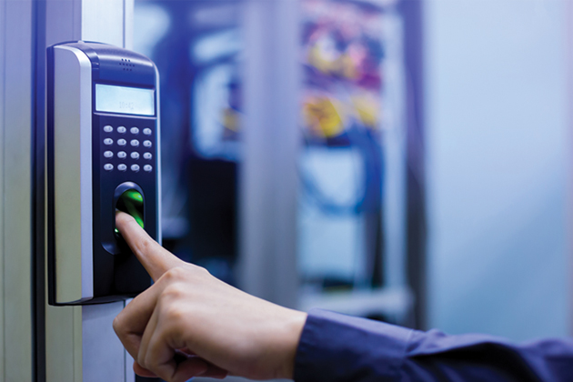 A person's hand pressing a pointer finger to a fingerprint reader machine outside an establishment.