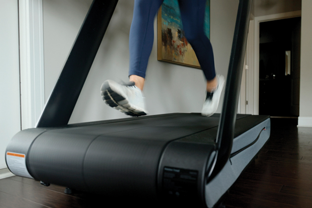 A person's legs and feet running on a treadmill.