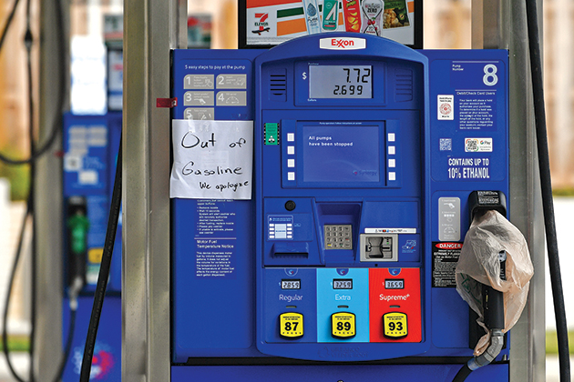 An Exxon gas pump that has a hand-written sign taped to the pump saying 