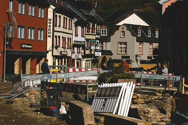 A European street strewn with wreckage from a flood, including bricks and signs.