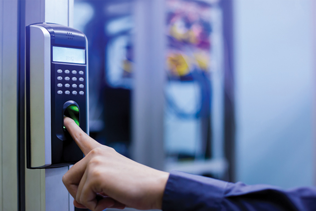 A person's hand pressing a pointer finger to a fingerprint reader machine outside an establishment.