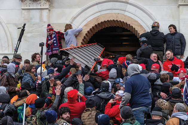 The January 6, 2021 riot in Washington, DC. The image shows the rioters breaching a door using a ladder as a battering ram.