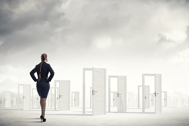 A woman in a business suit stands in front of a landscape of white open doorways with her hands on her hips.