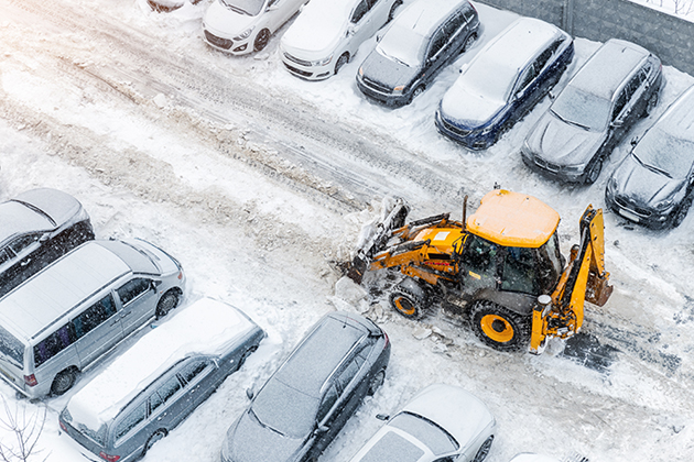 Snow plow plowing snow from a parking lot