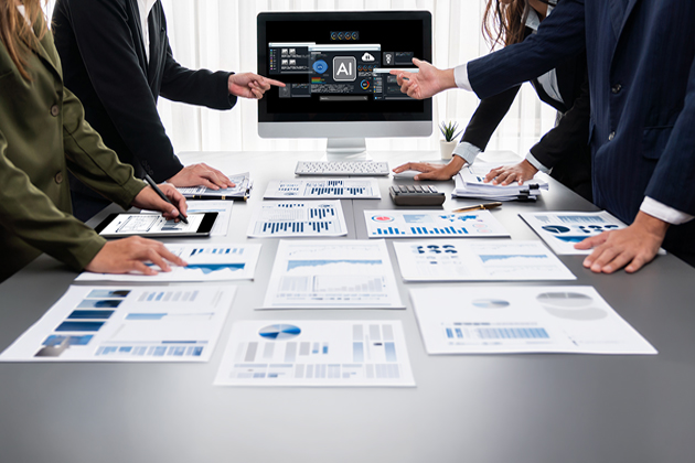 People standing around a desk looking at papers of graphs and charts with a computer screen with AI front and center.